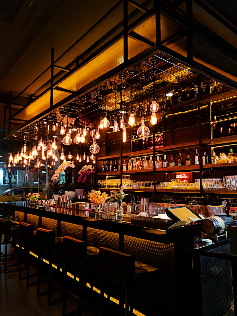 Moody bar interior with Edison bulb chandelier and full back bar of spirits
