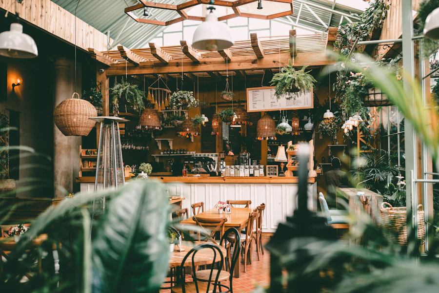 Garden cafe interior with lush hanging plants, warm wood tables — the type of space Brewman Coffee Concept occupies in An Thuong