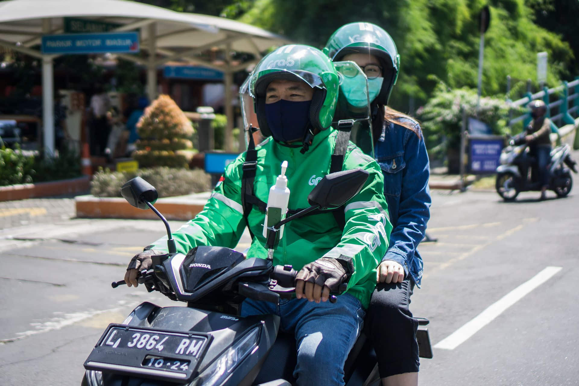 Grab driver waiting on motorbike checking phone