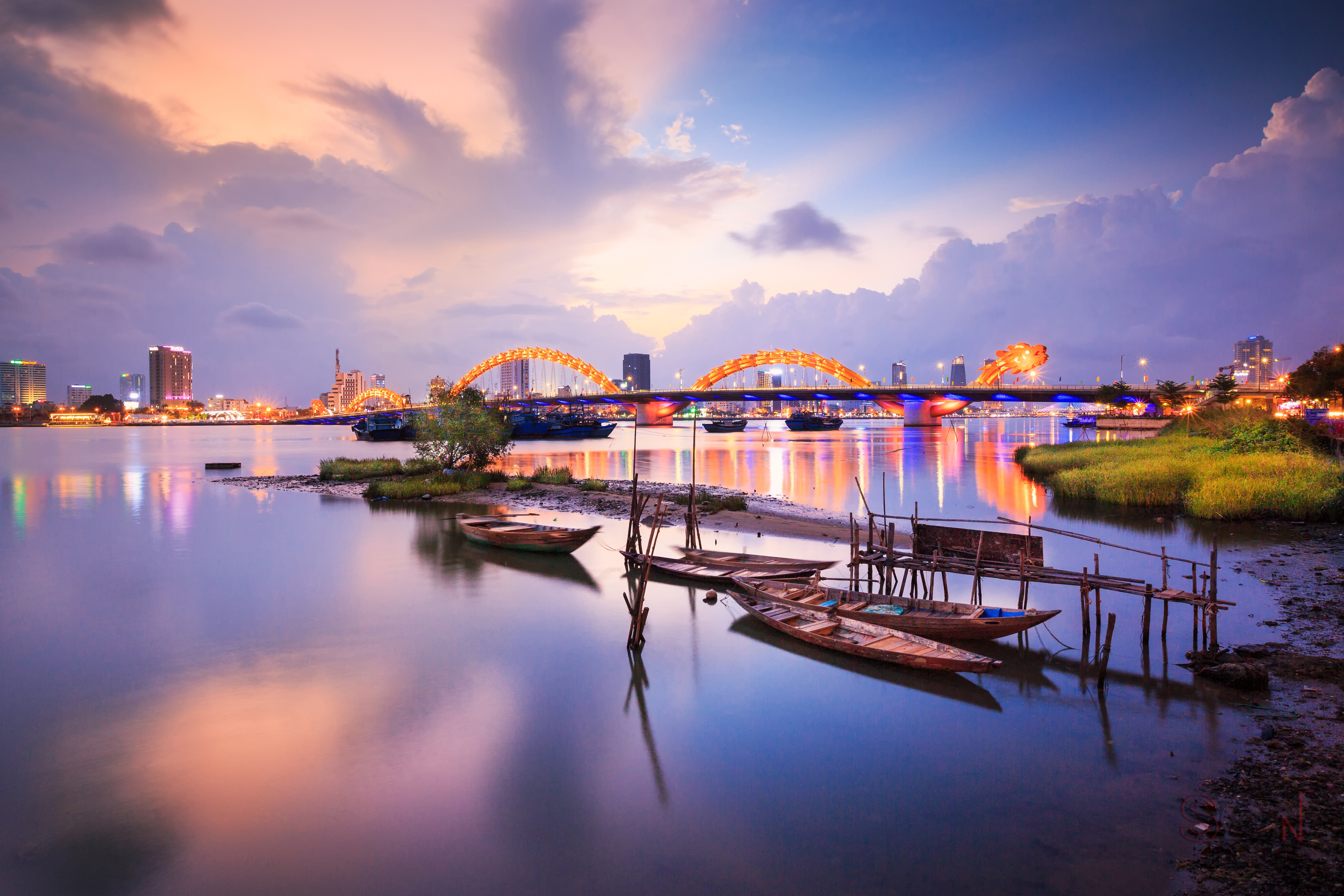 Dragon Bridge Da Nang illuminated purple against sunset sky