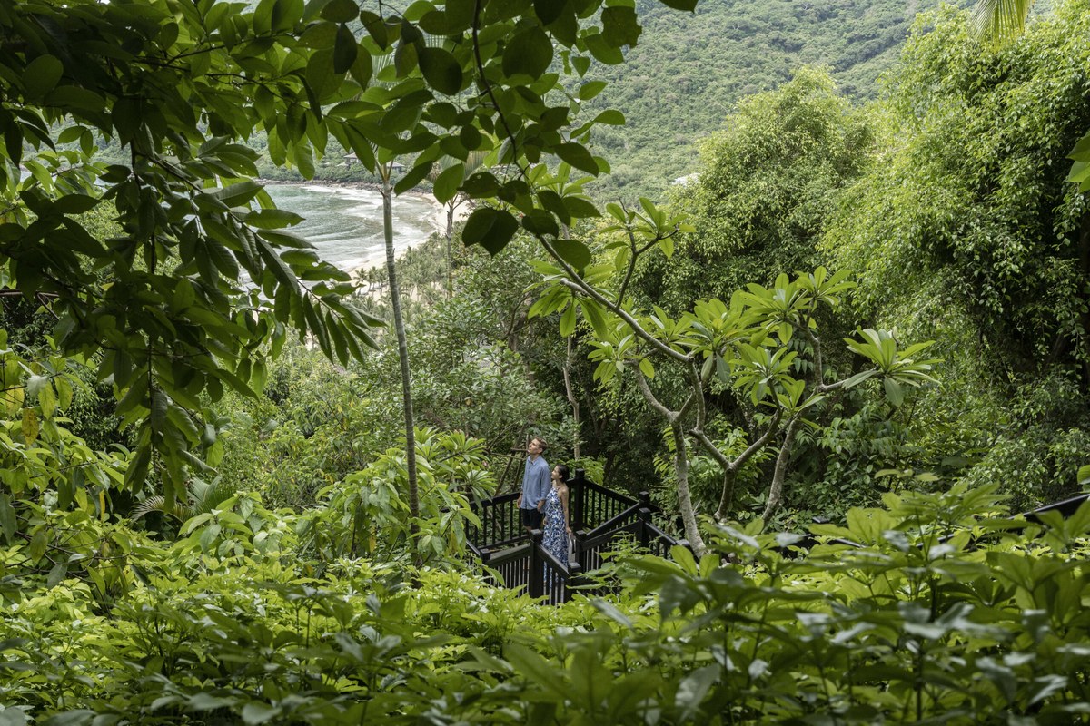 Couple on jungle walkway at InterContinental Danang Sun Peninsula Resort with private bay below