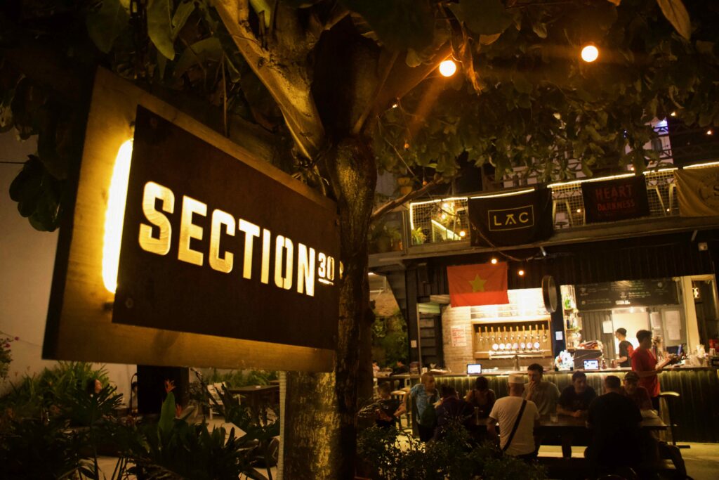 Section 30 Da Nang — lit venue sign at night, beer taps and outdoor bar visible